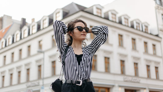 Mulher em look street style com camisa de listras preto e branco