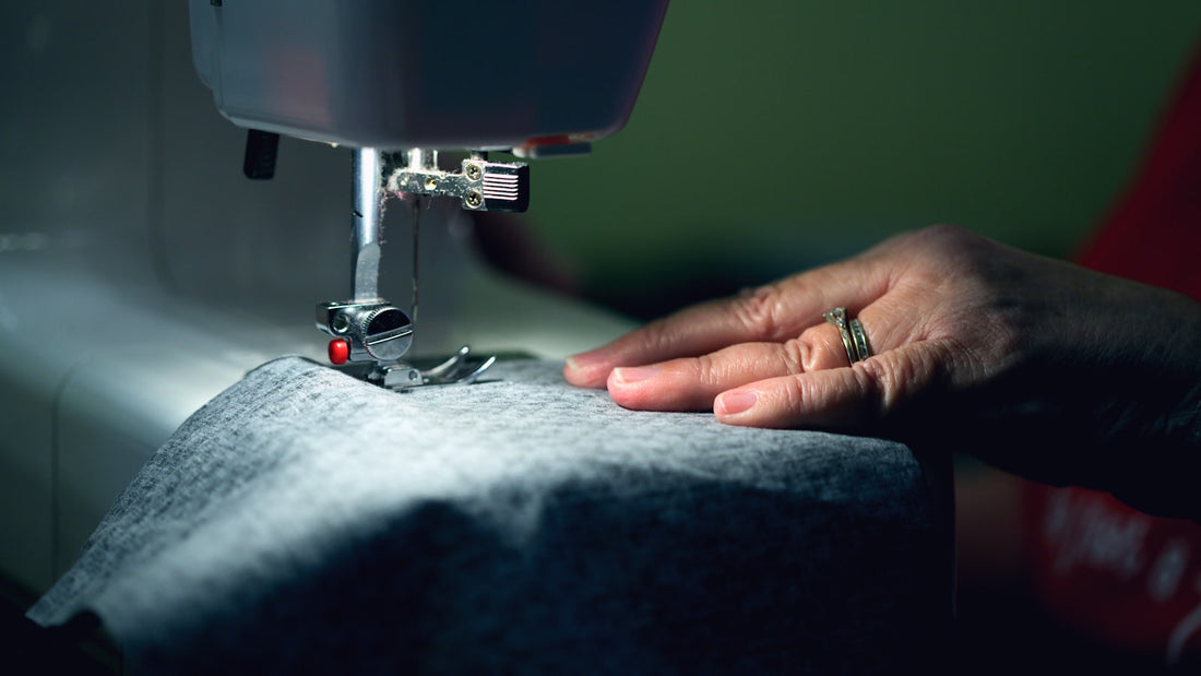 Mãos costurando tecido em máquina de costura, roupas personalizadas