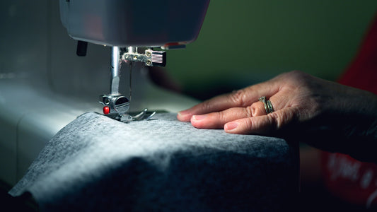Mãos costurando tecido em máquina de costura, roupas personalizadas
