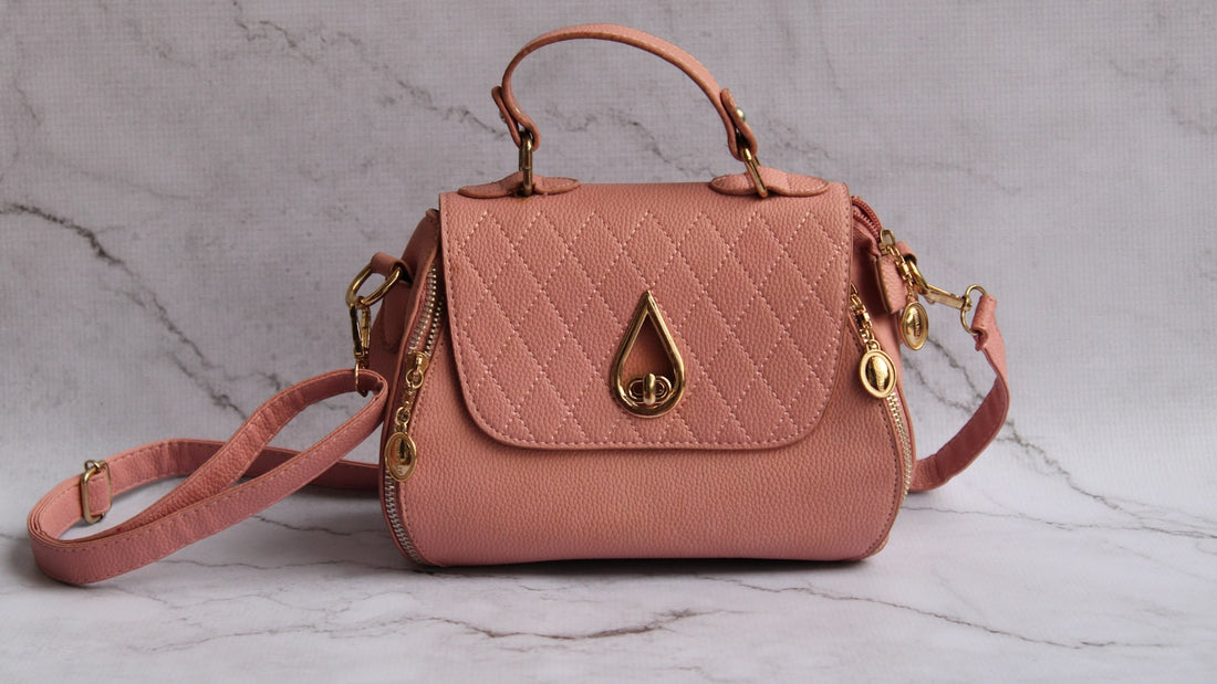 Bolsa transversal rosa feminina com alça longa sobre superfície de mármore